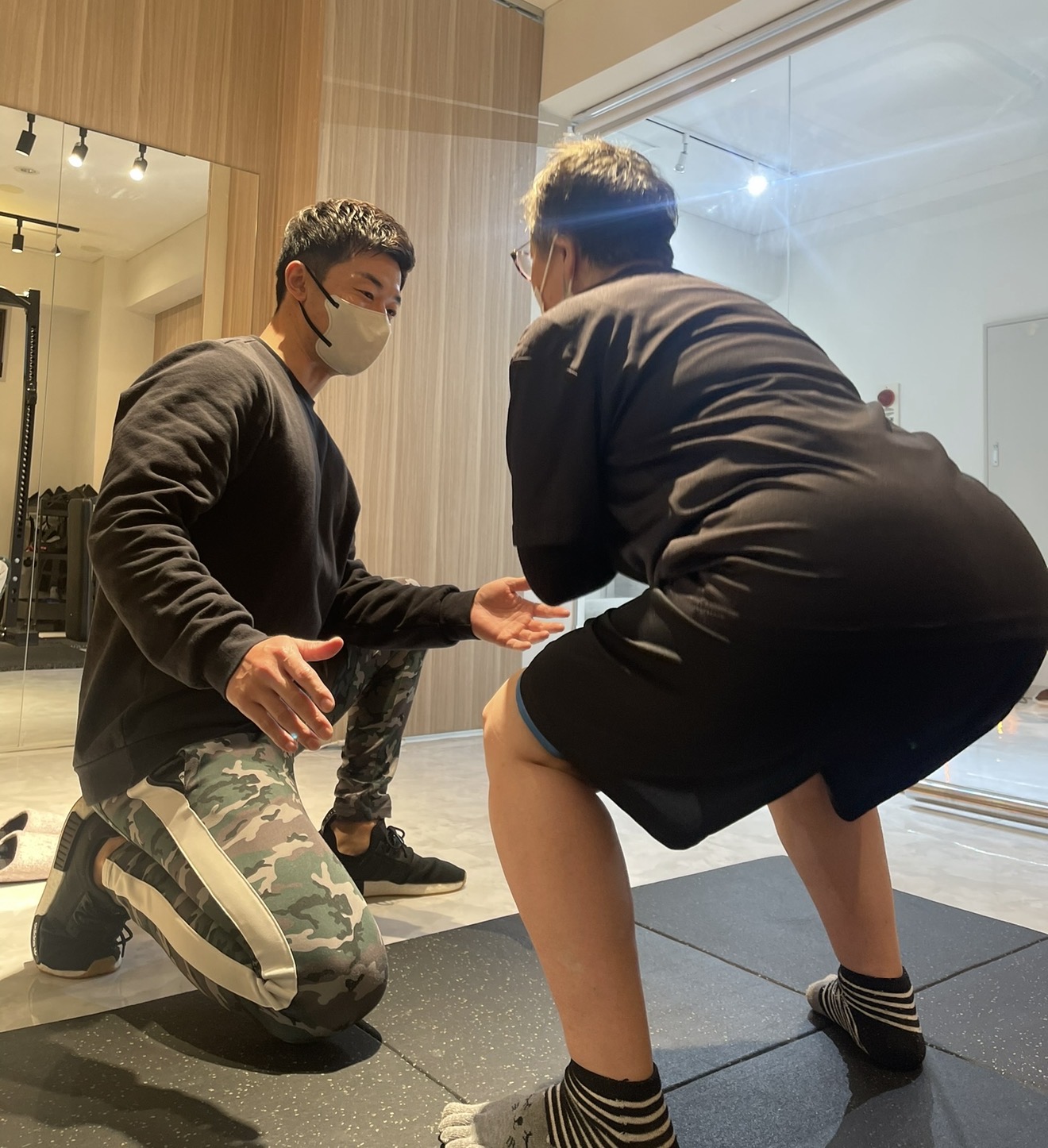 60代の方がパーソナルトレーナーのサポートを受けながら、安全に配慮した運動を行っている様子