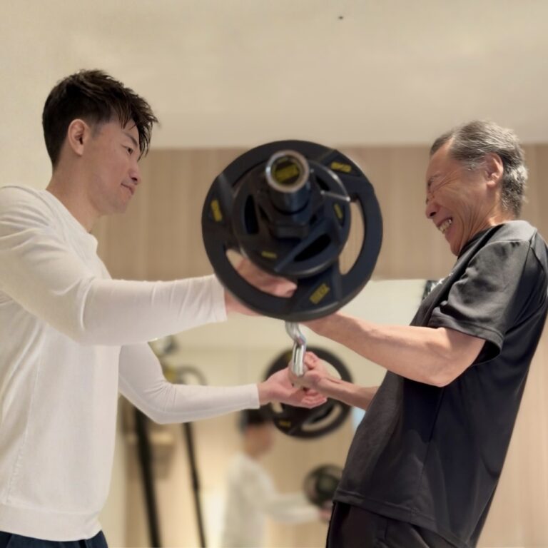 60代の男性がマンツーマン指導で、安全に配慮しながら筋力トレーニングに取り組んでいる様子
